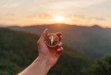 Hand holding up compass with mountains in the background