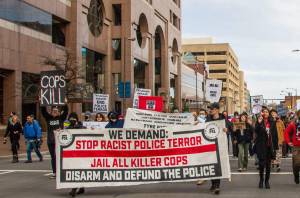 A group of protestors march with a sign that says 